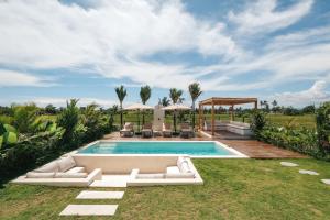 an outdoor pool with white furniture and a villa at Botanique Villa & Studio in Tanah Lot