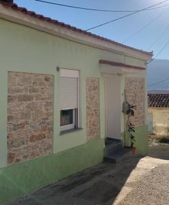 a green and white house with a door and a window at Iras in Samos