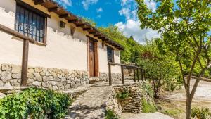 a house with a stone wall and a wooden door at La Huerta del Tajo - Pequeña Ronda by Ruralidays in Ronda