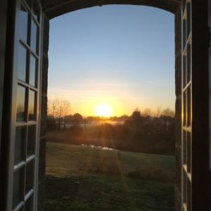 een open raam met uitzicht op de zonsondergang bij Maison de Maître - chambre chez particulier in Landéan