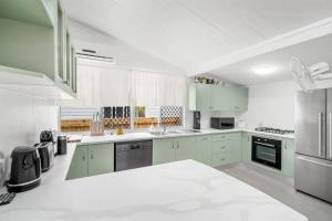una cocina con armarios y electrodomésticos verdes y blancos en Inner City Serenity en Cairns