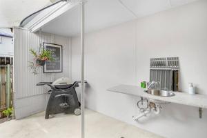 a white kitchen with a sink and a grill at Inner City Serenity in Cairns