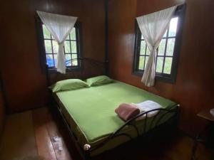 1 Schlafzimmer mit einem grünen Bett und 2 Fenstern in der Unterkunft Pinks Bungalow in Baan Tai