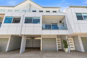 un grand bâtiment blanc avec deux garages dans l'établissement Smooth Sailing -Modern 2 bedroom apartment!, à Bellara