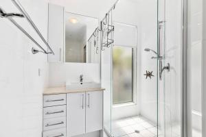 baño blanco con ducha y lavamanos en Smooth Sailing -Modern 2 bedroom apartment!, en Bellara