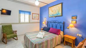 ein blaues Schlafzimmer mit einem Bett und einem Stuhl in der Unterkunft El Castillejo Alpandeire by Ruralidays in Alpandeire + 26 Fotos