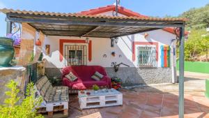 eine Terrasse mit einem roten Stuhl unter einer Pergola in der Unterkunft El Castillejo Alpandeire by Ruralidays in Alpandeire