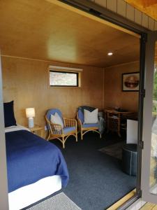 1 Schlafzimmer mit einem Bett, 2 Stühlen und einem Schreibtisch in der Unterkunft Glenwood Akaroa Bush Retreat - Totara Hut in Akaroa