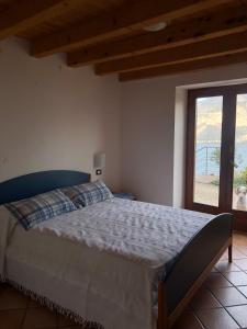 Un dormitorio con una cama grande y una ventana. en Casa Margherita, en Brenzone sul Garda