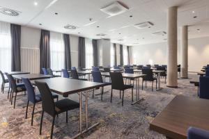 une salle de conférence avec des tables, des chaises et des fenêtres dans l'établissement Select Hotel Augsburg, à Neusäß