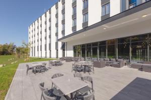 a patio with tables and chairs in front of a building at Select Hotel Augsburg in Neusäß
