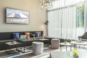 a living room with a couch and a tv on the wall at Select Hotel Augsburg in Neusäß