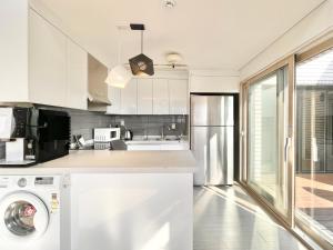 a kitchen with white cabinets and a washer at Koin Guesthouse Incheon airport in Incheon