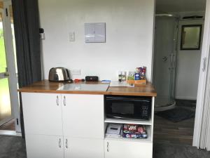 a kitchen counter with a microwave and a sink at Farmland retreat in Tokoroa