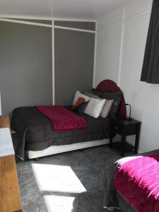 um quarto com uma cama com lençóis vermelhos e almofadas brancas em Farmland retreat em Tokoroa