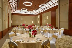 un salón de banquetes con mesas y sillas blancas y flores rojas en Taj Wayanad Resort & Spa, Kerala en Wayanad