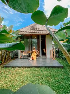 a woman sitting at a table on the porch of a house at Ecozy Dijiwa Canggu in Canggu