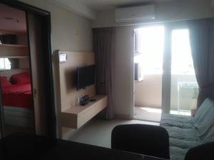 a room with a bed and a television and a window at Mg Suite 1bedroom Apartment by Just Inn Management in Semarang
