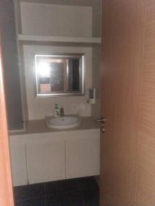 La salle de bains est pourvue d'un lavabo et d'un miroir. dans l'établissement Mg Suite 1bedroom Apartment by Just Inn Management, à Semarang