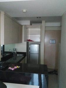 La cuisine est équipée d'un évier et d'un réfrigérateur. dans l'établissement Mg Suite 1bedroom Apartment by Just Inn Management, à Semarang
