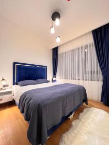 Un dormitorio con una gran cama azul con cortinas azules en Mükemmel konumda şehir manzaralı ve balkonlu daire, en Estambul
