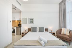 a bedroom with a large white bed and a kitchen at Urban Studio at The Square Tower Jumeirah Village Circle by Deluxe Holiday Homes in Dubai