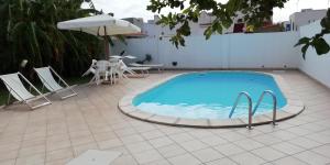 una piscina con sillas, una mesa y una sombrilla en Casa Marinella, en Marinella di Selinunte