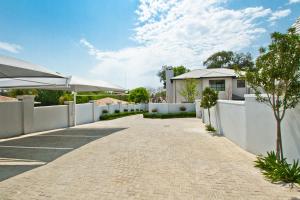 a driveway of a house with a white fence at Kent Manor Guest Suites in Johannesburg