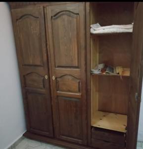 a wooden cabinet with wooden doors in a room at غرفة فردية خاصة للاناث in Bel Aroussi