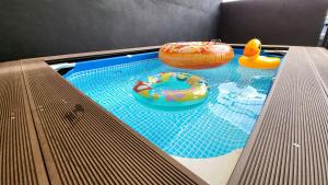 a swimming pool with two donuts and other toys at Eisya Guest House Perlis With Pool MUSLlM ONLY in Arau