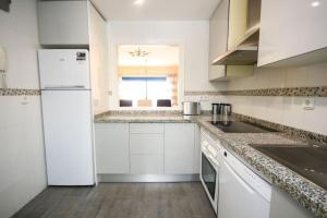 eine weiße Küche mit einer Spüle und einem Kühlschrank in der Unterkunft 2 bedrooms sea and pool view apt in Duquesa Golf & Gardens Manilva in Castillo de Sabinillas