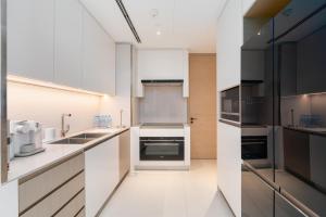 a large kitchen with white cabinets and appliances at Lux BnB I The Address JBR I Ocean View in Dubai