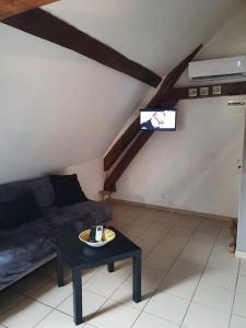 ein Wohnzimmer mit einem Sofa und einem Tisch in der Unterkunft La Mansarde: appartement tout confort à Vatan in Vatan