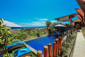 a swimming pool with a fence and an umbrella at You and We House in Nusa Penida