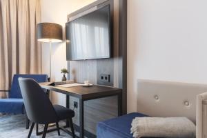 アウクスブルクにあるCandlewood Suites Augsburg by IHGのデスクと青い椅子が備わる客室です。