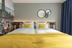 - une chambre avec un grand lit et une couverture en or dans l'établissement acora Augsburg Living the City, à Neusäß