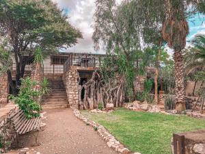 un giardino con alberi e passerella in pietra di Nkisi Guesthouse a Kang