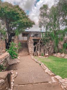 un camino de piedra frente a un edificio con árboles en Nkisi Guesthouse en Kang