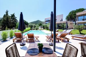 a patio with a table and chairs and a swimming pool at Elies Aesthetic Living in Iraklitsa