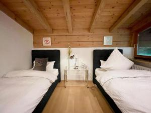two beds in a room with wooden ceilings and a table at whole villa Munich, Alps view, Quiet and spacious in Feldkirchen-Westerham
