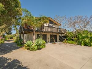 una casa con una palmera frente a una entrada en Jacaranda Lodge - Whangamata Upstairs Unit en Whangamata