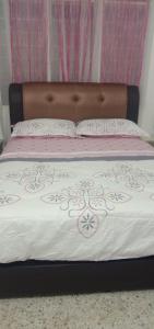 a bed with a brown headboard and pink and white sheets at AZhomestay in Jitra