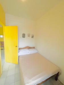 Dormitorio pequeño con cama con puerta amarilla en The Pearl byTERBAIKhome, en Puerto Princesa City