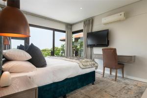 a bedroom with a bed and a television and a chair at Luxury 3 Bed Villa- Zimbali Coastal Resort Retreat in Ballito