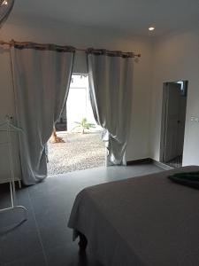a bedroom with a bed and a window with curtains at Little Escape Guesthouse Nesat in Phumĭ Chroŭy Svay +13 photos