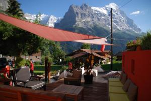 a patio with a table and chairs and a mountain at Hotel Lauberhorn - Home for Outdoor Activities in Grindelwald