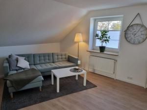 een woonkamer met een bank, een tafel en een klok bij Ferienwohnung am Springerhof in Schönefeld