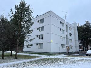 a white apartment building with snow on the ground at Northern Lights Center Apartment 2 in Rovaniemi