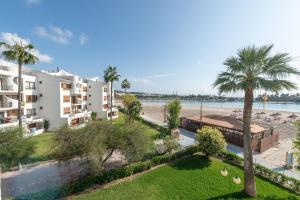 un complejo de apartamentos con palmeras y playa en Apartment Rovelló - Port d'Alcúdia en Puerto de Alcúdia
