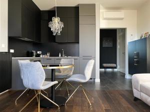 a kitchen with white chairs and a dining table at visiting apartments - Wyspa Słodowa in Wrocław